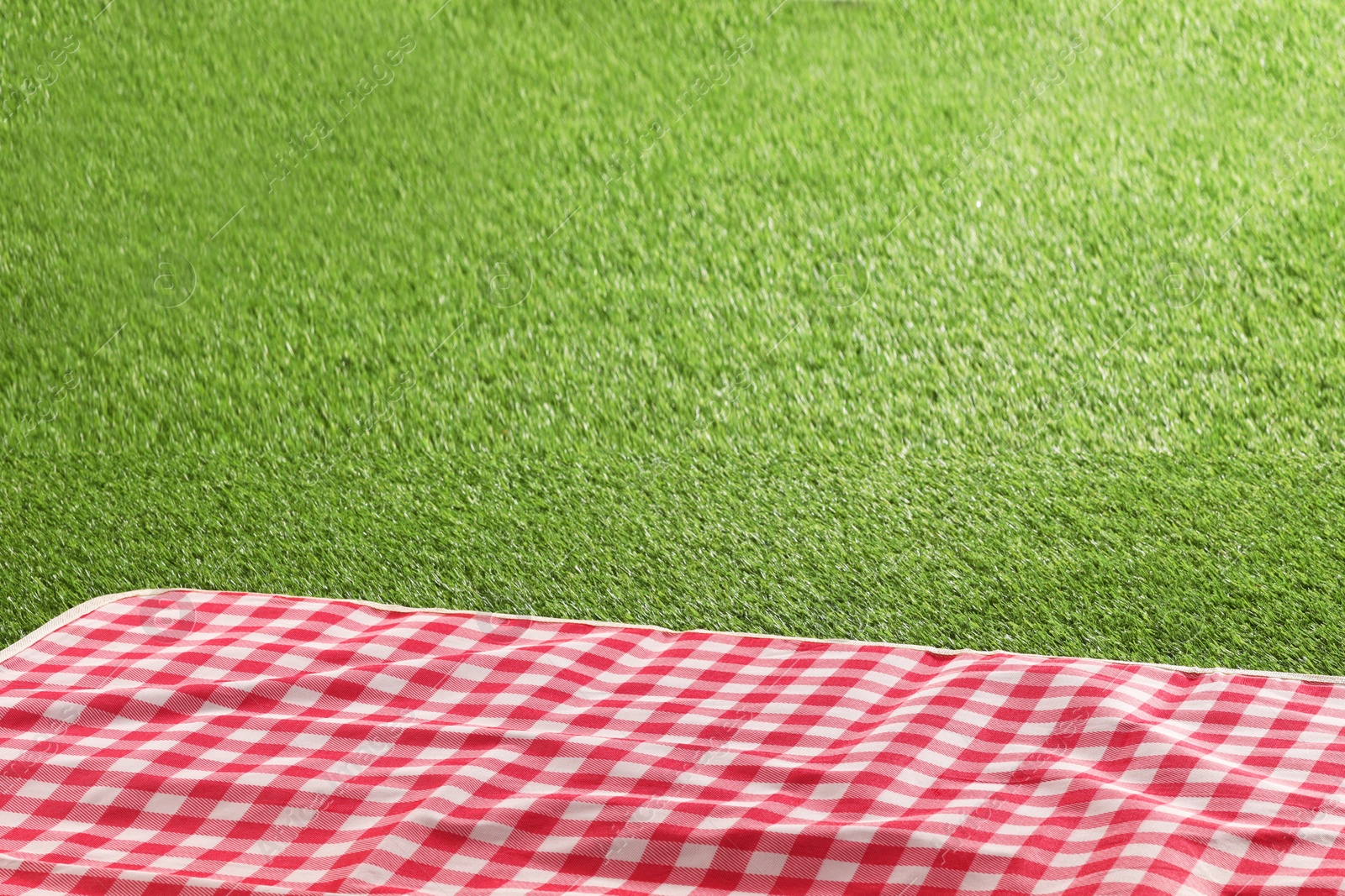 Checkered picnic tablecloth on green grass, closeup. Space for text Photo of Checkered picnic tablecloth on green grass, closeup. Space for text