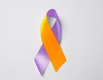 World Psoriasis Day. Orange and orchid awareness ribbon as symbol of support on white background, top view