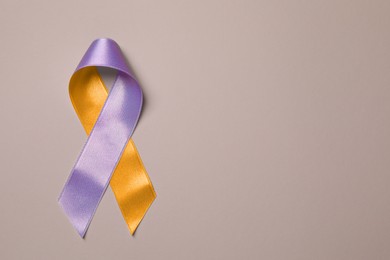 Image of World Psoriasis Day. Orange and orchid awareness ribbon as symbol of support on dark beige background, top view. Space for text