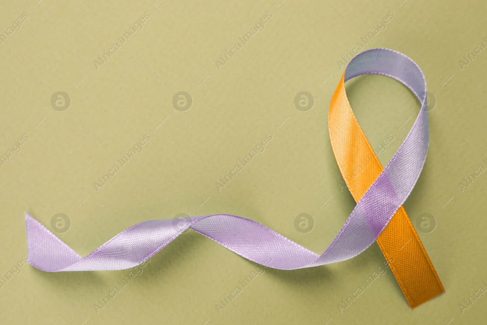 Image of World Psoriasis Day. Orange and orchid awareness ribbon as symbol of support on olive color background, top view. Space for text