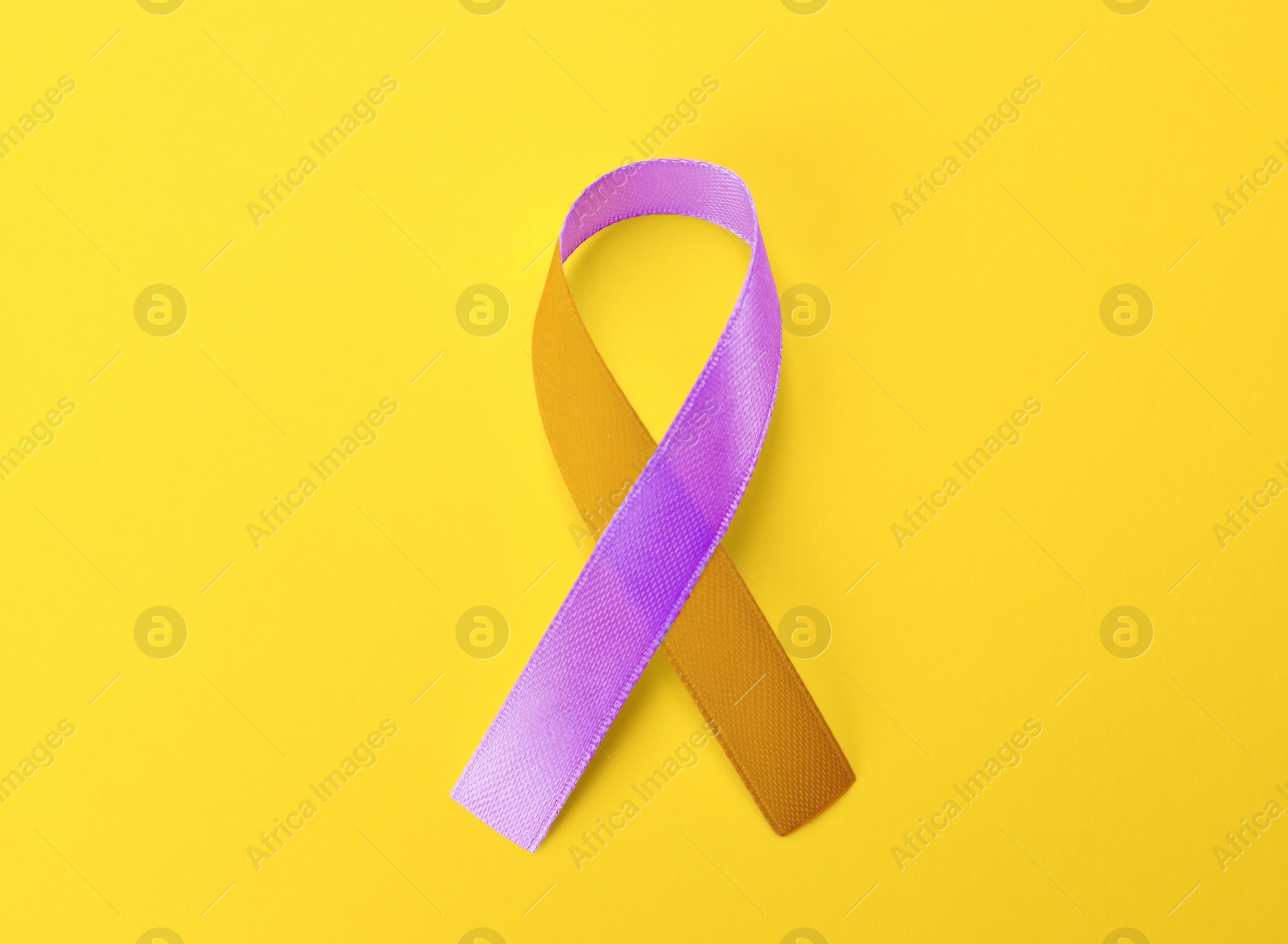 Image of World Psoriasis Day. Orange and orchid awareness ribbon as symbol of support on yellow background, top view