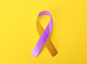 Image of World Psoriasis Day. Orange and orchid awareness ribbon as symbol of support on yellow background, top view