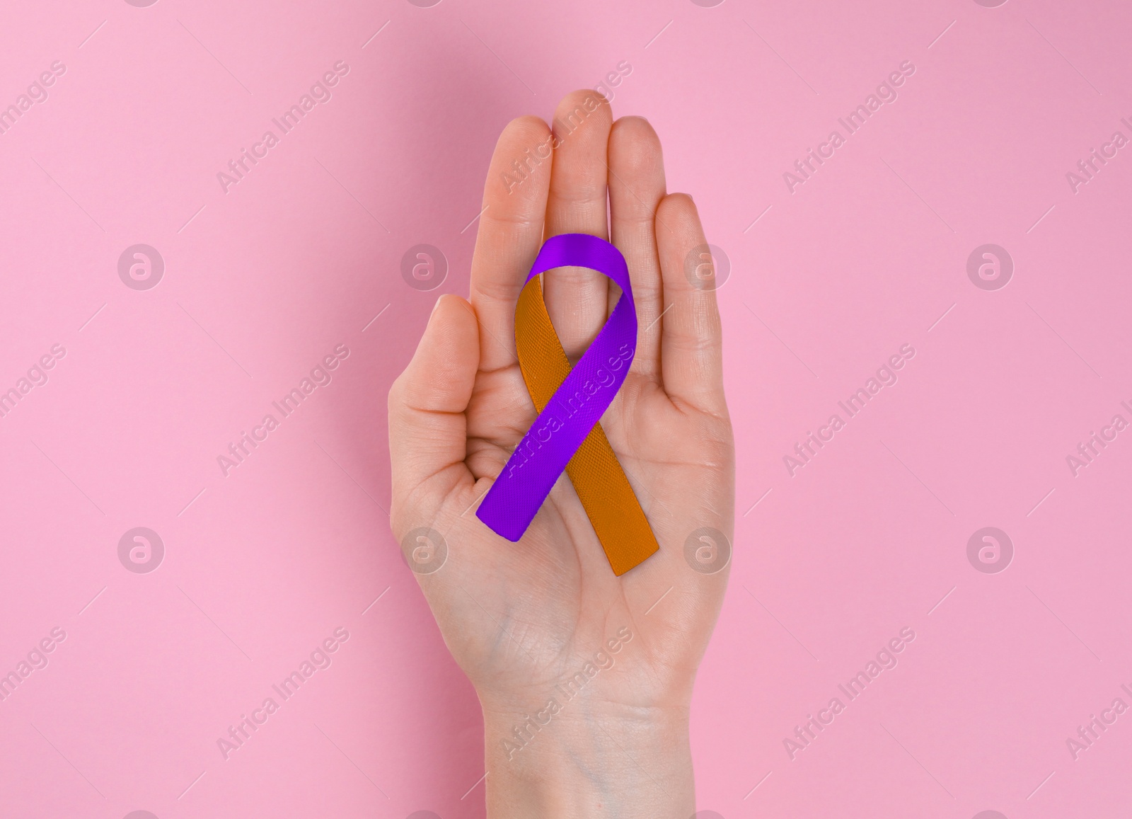 Image of World Psoriasis Day. Woman with orange and orchid ribbon as symbol of support on pink background, top view