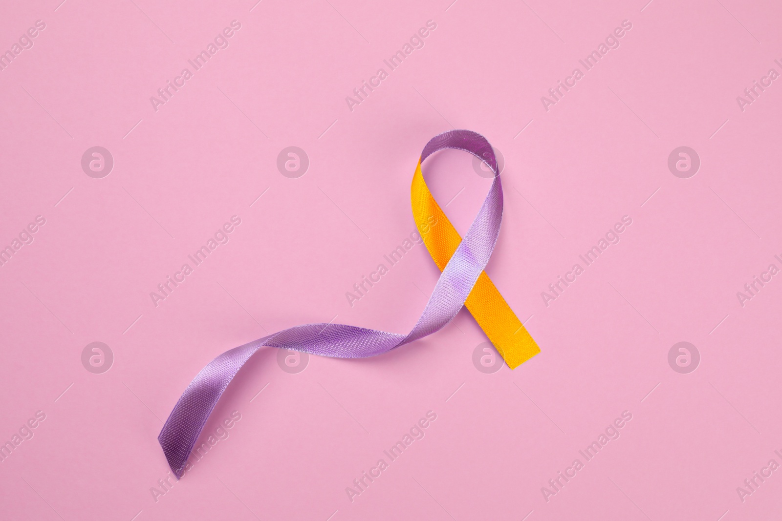 Image of World Psoriasis Day. Orange and orchid awareness ribbon as symbol of support on pink background, top view. Space for text