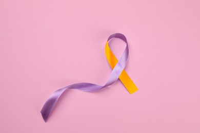 Image of World Psoriasis Day. Orange and orchid awareness ribbon as symbol of support on pink background, top view. Space for text