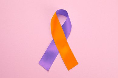 Image of World Psoriasis Day. Orange and orchid awareness ribbon as symbol of support on pink background, top view