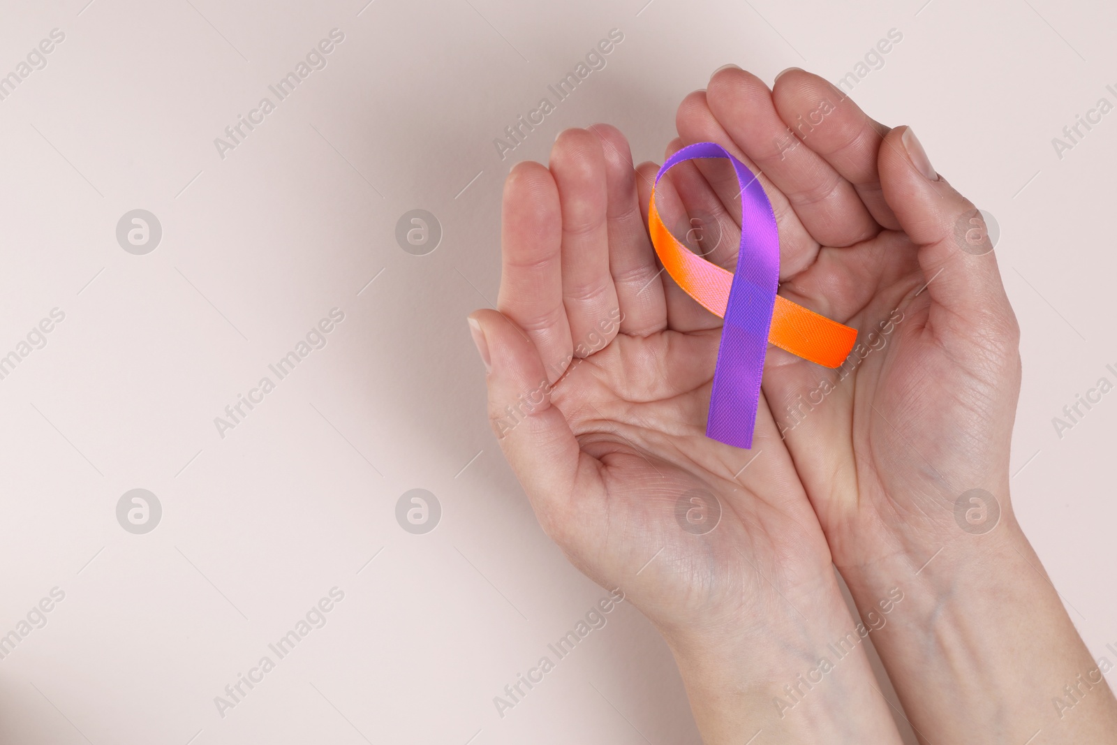 Image of World Psoriasis Day. Woman with orange and orchid ribbon as symbol of support on beige background, top view. Space for text