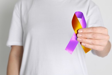 Image of World Psoriasis Day. Woman with orange and orchid ribbon as symbol of support on white background, closeup