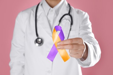 Image of World Psoriasis Day. Doctor with orange and orchid ribbon as symbol of support on pink background, closeup