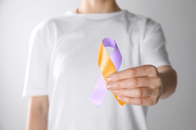 Image of World Psoriasis Day. Woman with orange and orchid ribbon as symbol of support on white background, closeup