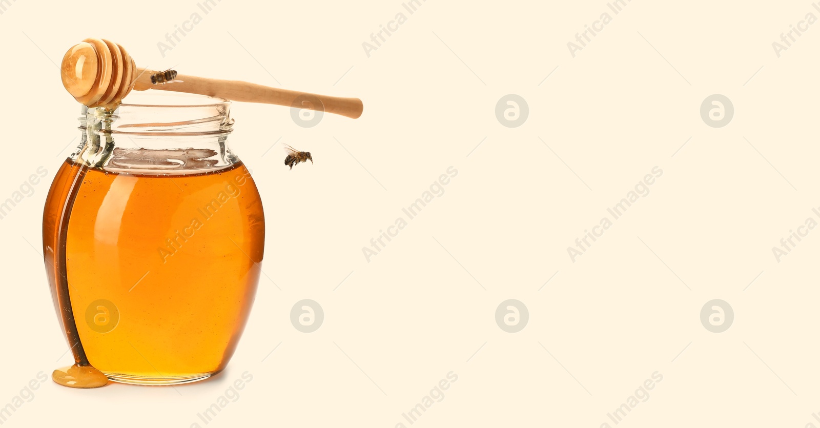 Image of Organic honey in glass jar, wooden dipper and bees on light background. Banner design with space for text