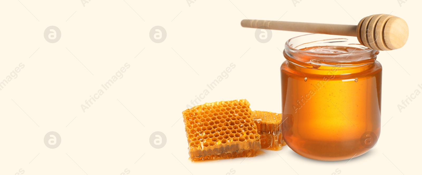 Image of Organic honey in glass jar, wooden dipper and honeycomb on beige background. Banner design with space for text