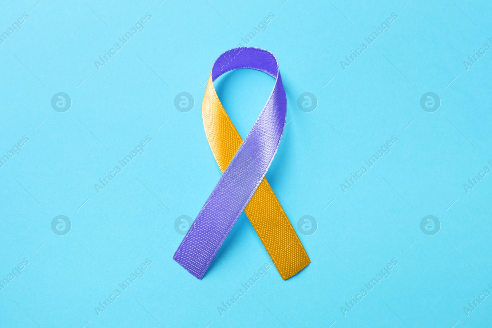 Image of World Psoriasis Day. Orange and orchid awareness ribbon as symbol of support on light blue background, top view