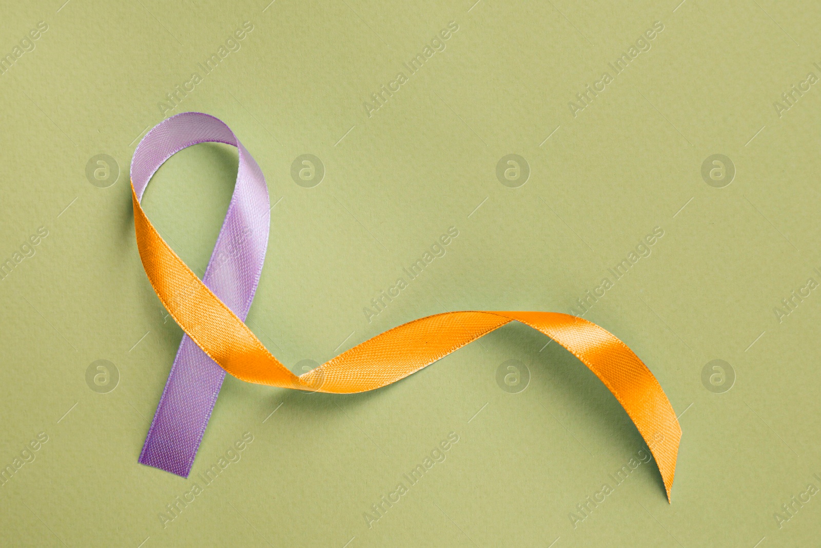 Image of World Psoriasis Day. Orange and orchid awareness ribbon as symbol of support on olive color background, top view. Space for text