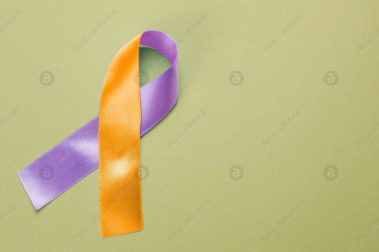 Image of World Psoriasis Day. Orange and orchid awareness ribbon as symbol of support on olive color background, top view. Space for text