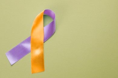 Image of World Psoriasis Day. Orange and orchid awareness ribbon as symbol of support on olive color background, top view. Space for text