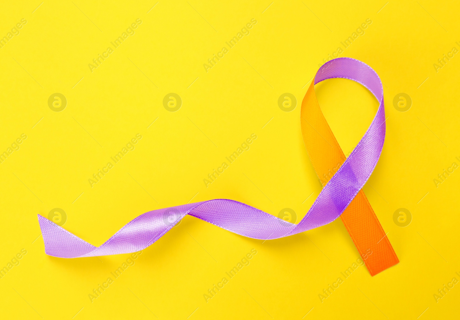 Image of World Psoriasis Day. Orange and orchid awareness ribbon as symbol of support on yellow background, top view. Space for text