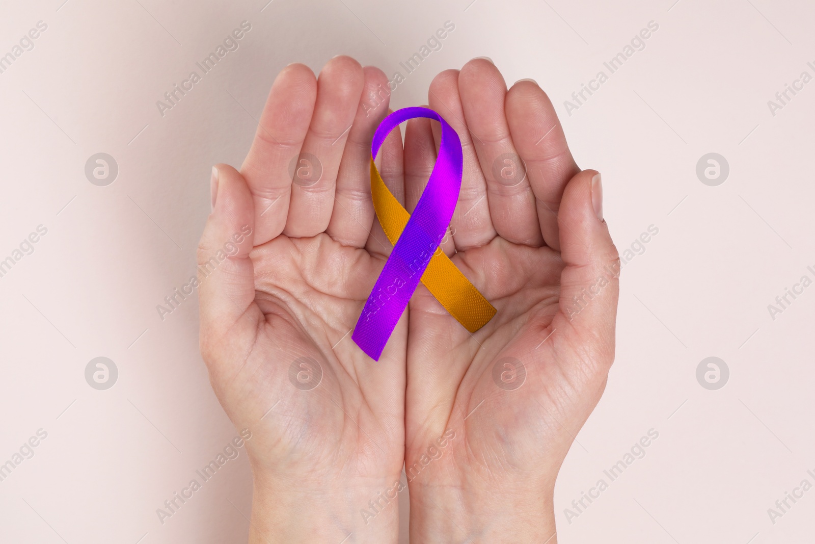 Image of World Psoriasis Day. Woman with orange and orchid ribbon as symbol of support on beige background, top view