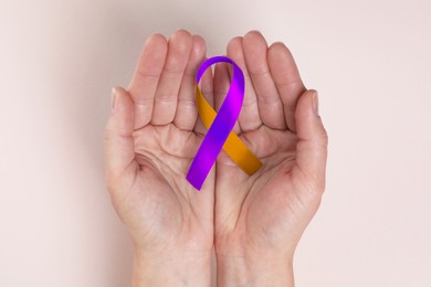 Image of World Psoriasis Day. Woman with orange and orchid ribbon as symbol of support on beige background, top view