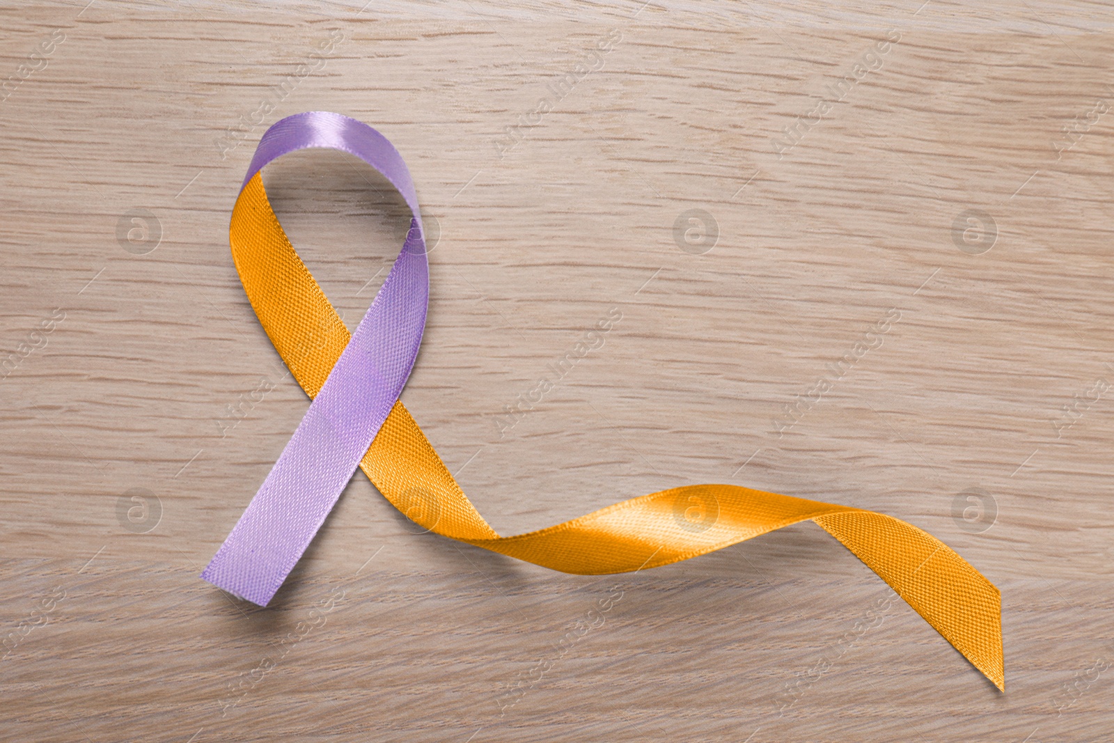 Image of World Psoriasis Day. Orange and orchid awareness ribbon as symbol of support on wooden background, top view. Space for text