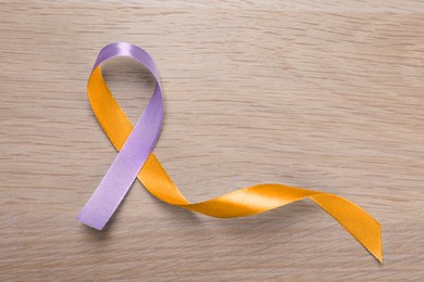 World Psoriasis Day. Orange and orchid awareness ribbon as symbol of support on wooden background, top view. Space for text