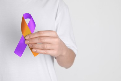 Image of World Psoriasis Day. Woman with orange and orchid ribbon as symbol of support on white background, closeup