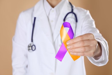 Image of World Psoriasis Day. Doctor with orange and orchid ribbon as symbol of support on dark beige background, closeup