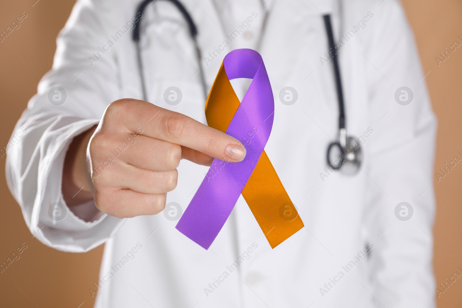 Image of World Psoriasis Day. Doctor with orange and orchid ribbon as symbol of support on dark beige background, closeup