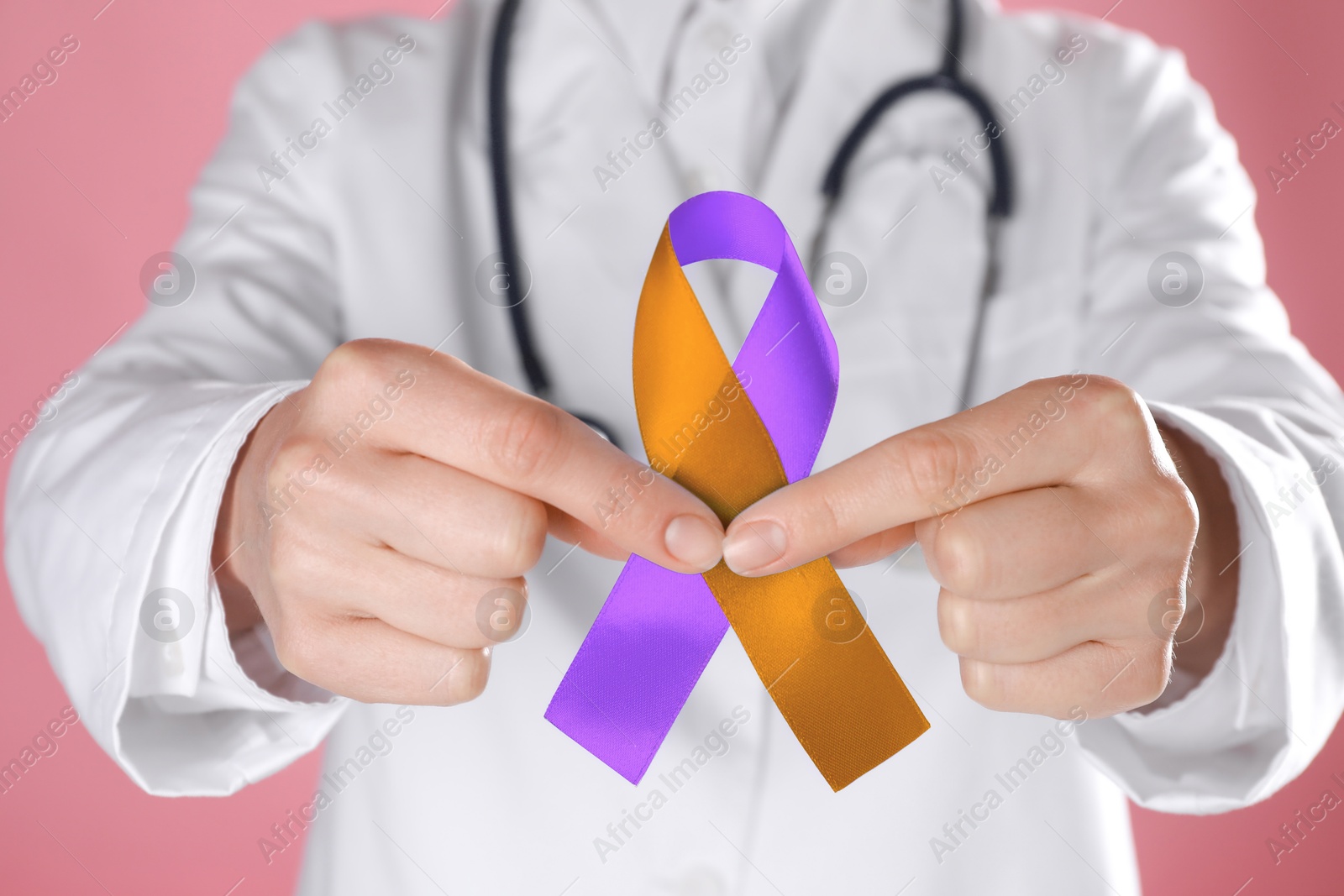 Image of World Psoriasis Day. Doctor with orange and orchid ribbon as symbol of support on pink background, closeup