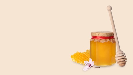 Image of Organic honey in glass jar, wooden dipper and honeycomb on beige background. Banner design with space for text