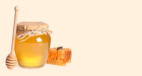 Image of Organic honey in glass jar, wooden dipper and honeycomb on beige background. Banner design with space for text