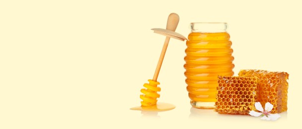 Image of Organic honey in glass jar, wooden dipper and honeycomb on beige background. Banner design with space for text