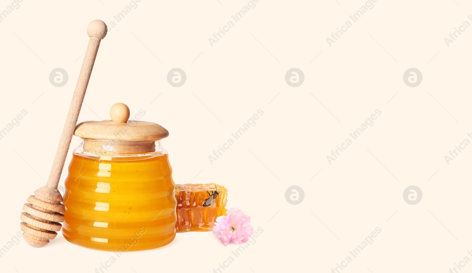 Image of Organic honey in glass jar, wooden dipper and honeycomb on light background. Banner design with space for text