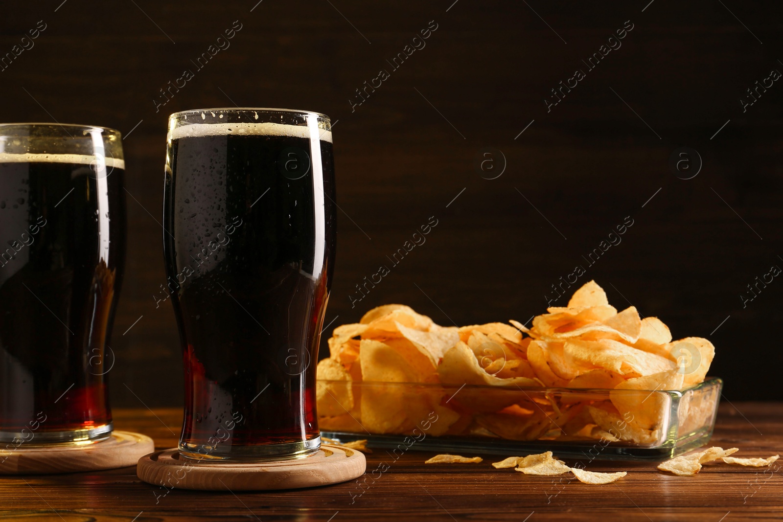 Photo of Glasses of beer and potato chips on wooden table