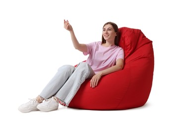 Smiling woman sitting on red bean bag chair against white background