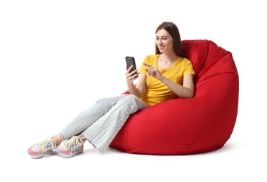 Photo of Smiling woman using smartphone while sitting on red bean bag chair against white background
