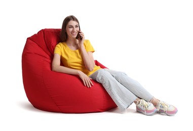 Smiling woman talking on smartphone while sitting on red bean bag chair against white background