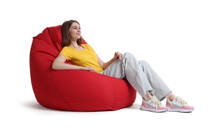 Beautiful young woman sitting on red bean bag chair against white background