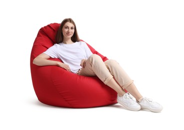 Beautiful young woman sitting on red bean bag chair against white background