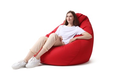 Beautiful young woman sitting on red bean bag chair against white background