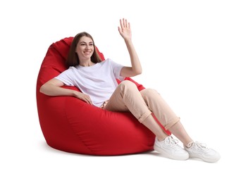 Happy woman sitting on red bean bag chair against white background