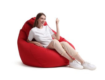 Happy woman sitting on red bean bag chair against white background