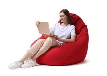 Photo of Beautiful young woman with laptop sitting on red bean bag chair against white background