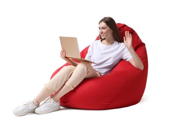 Photo of Beautiful young woman with laptop having online meeting while sitting on red bean bag chair against white background