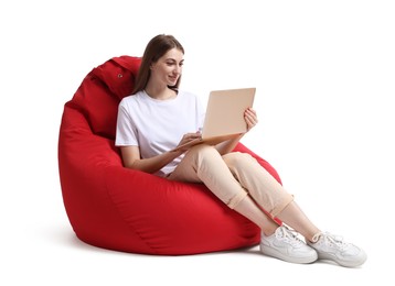 Photo of Beautiful young woman with laptop sitting on red bean bag chair against white background