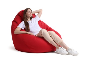 Beautiful young woman sitting on red bean bag chair against white background