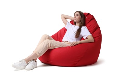 Beautiful young woman sitting on red bean bag chair against white background