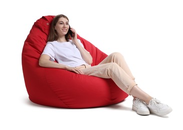 Photo of Beautiful young woman talking on smartphone while sitting on red bean bag chair against white background