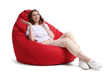 Photo of Beautiful young woman talking on smartphone while sitting on red bean bag chair against white background