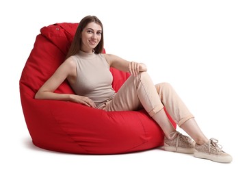 Smiling woman sitting on red bean bag chair against white background